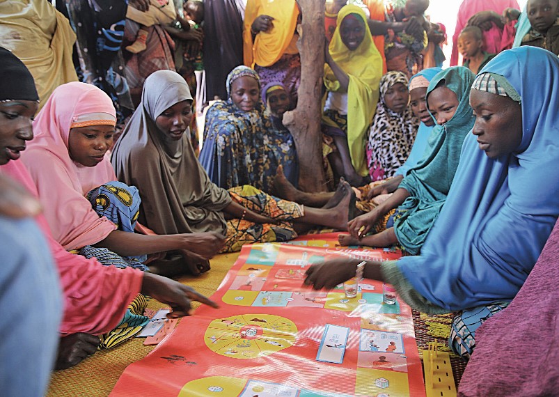 Un grupo de mujeres se reúne en torno a un juego de mesa de planificación familiar en Níger durante el diseño de adaptación de La Famille Idéale.